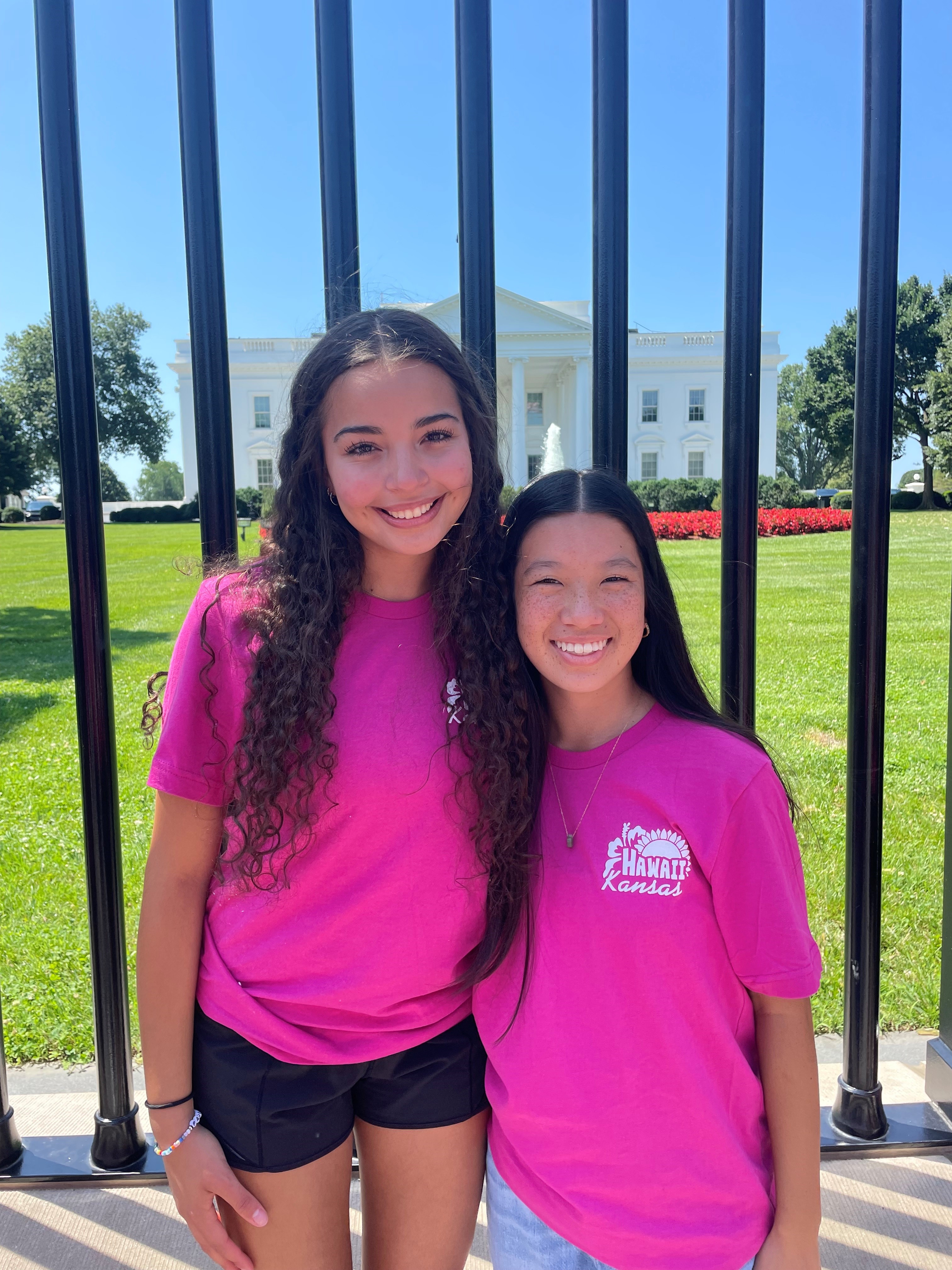 Two teenage girls standing in front of the fence by the White House