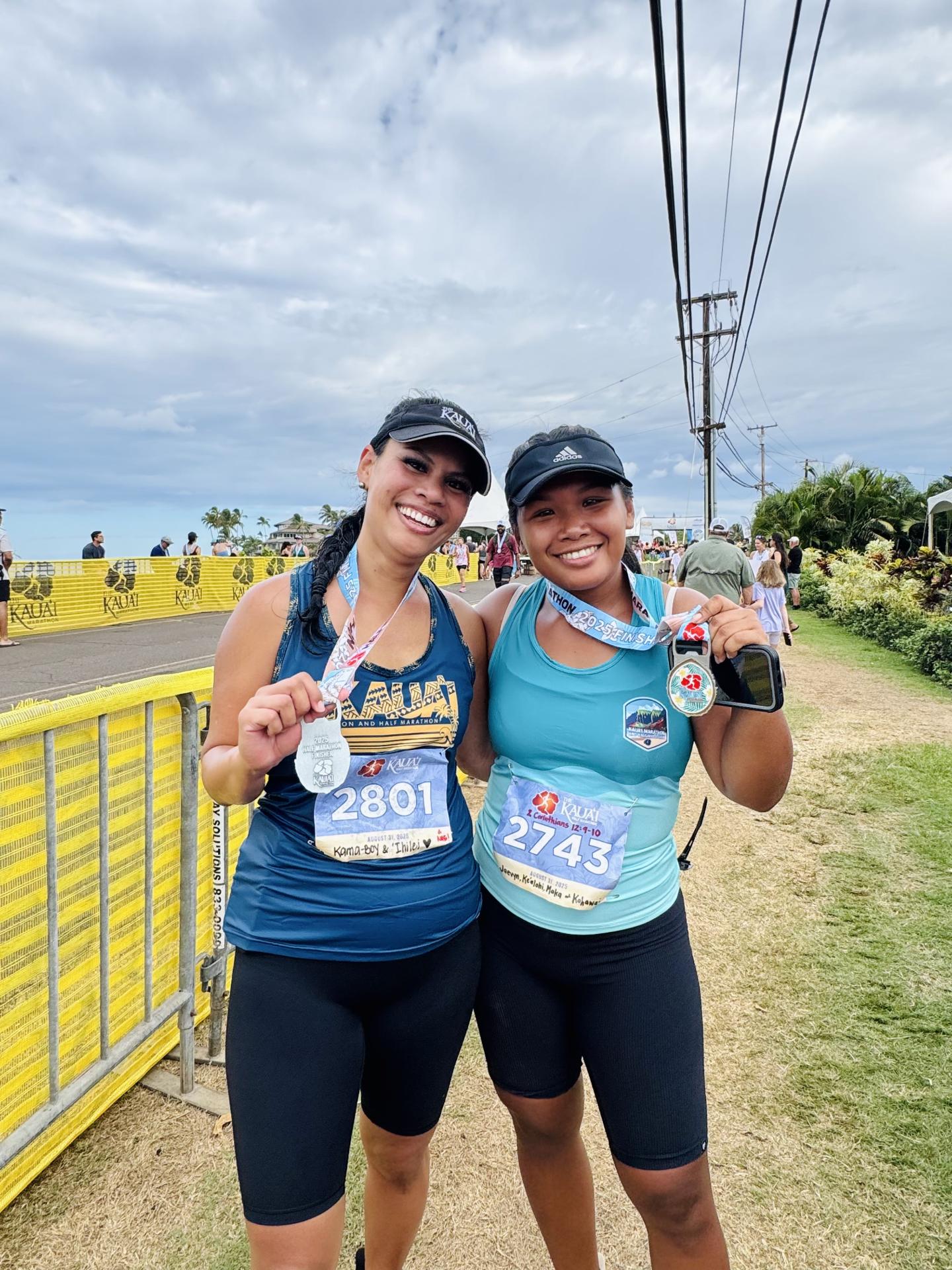 2 Women smiling holding medals